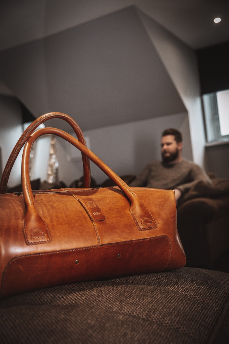 leather duffle bag with male in the background