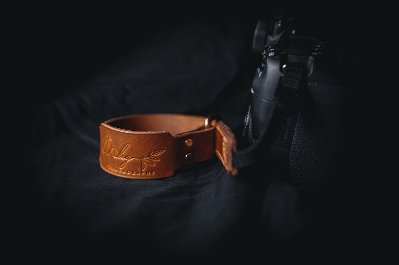 brown leather branded camera wrist strap attached to camera