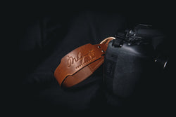 brown leather branded camera wrist strap attached to camera